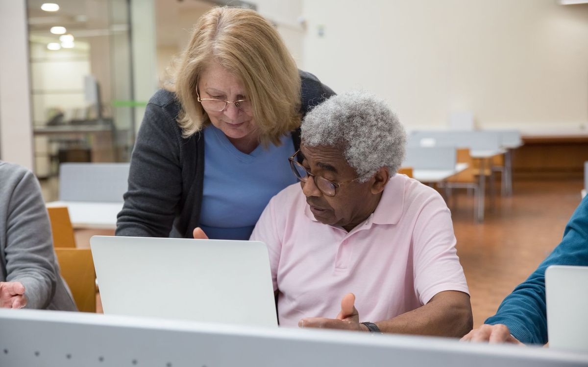 Rustige uitleg aan tafel door een vaste computerhulp